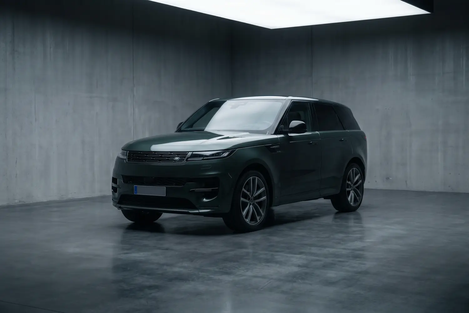 Range Rover Sport vert foncé dans un studio en béton.